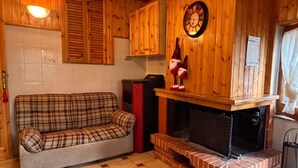 Un'accogliente stanza con un divano a quadri, mobili in legno, un camino e un orologio appeso al muro.