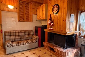 Ein gemütliches Zimmer mit einem Karomuster-Sofa, Holzschränken, einem Kamin und einer Wanduhr.
