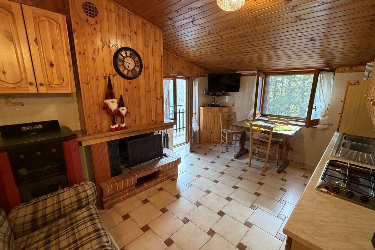 A wooden cabin interior with a fireplace, a dining area, and a kitchen.