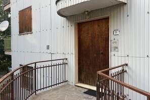 A building with a wooden door, a metal railing, and a stone staircase. - La Casa degli Gnomi - Fuscaldoapartment (Camigliatello Silano)