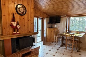 A wooden interior with a fireplace, a television mounted on the wall, and a dining area with chairs and a table. - La Casa degli Gnomi - Fuscaldoapartment (Camigliatello Silano)