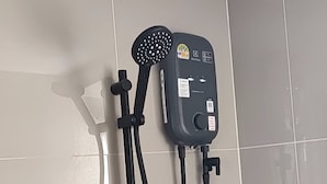 A wall-mounted shower unit with a handheld showerhead and control knobs. - Room-exclusive Holiday House in Thon Bur (Bangkok)
