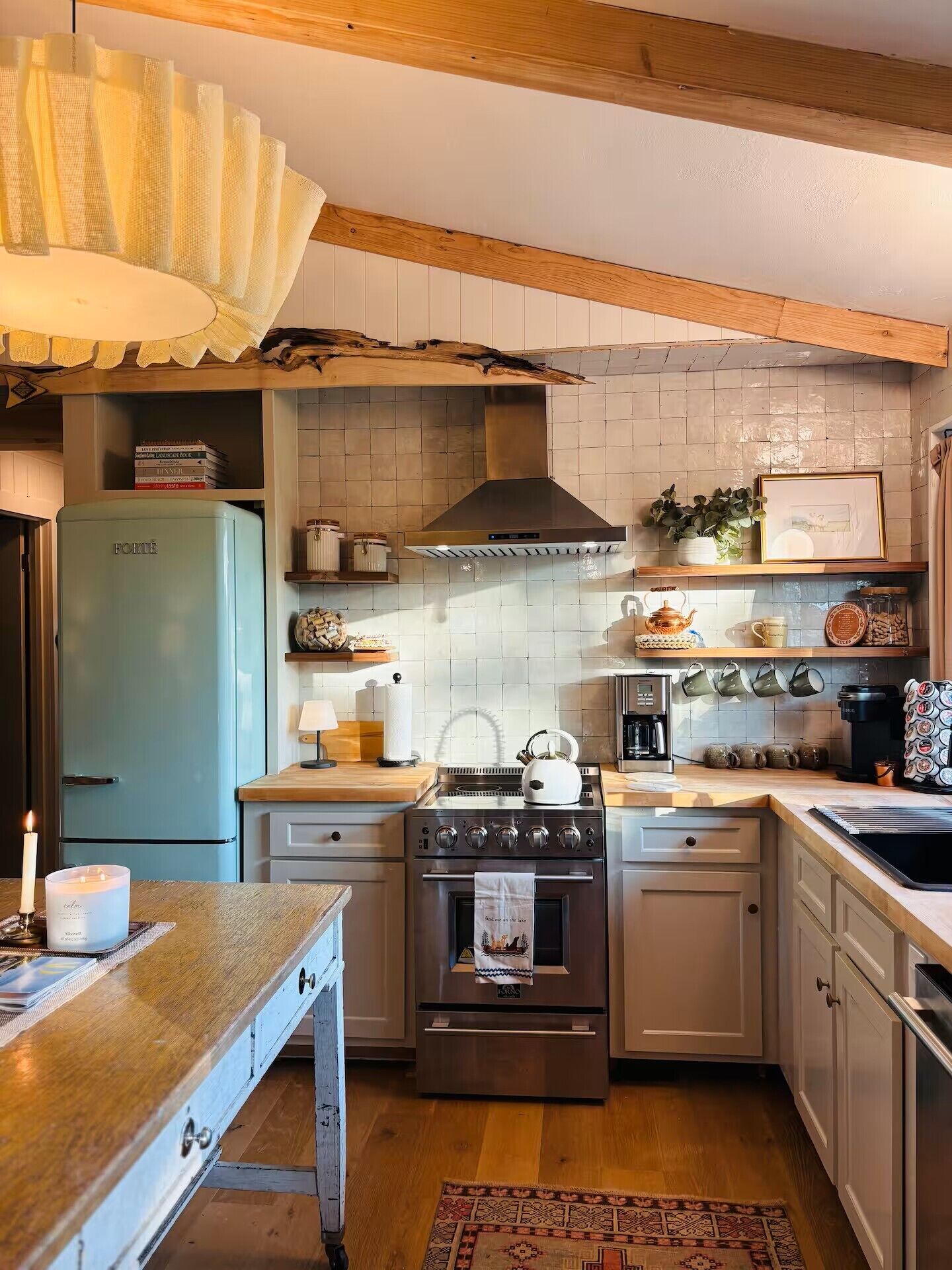 A kitchen with a blue refrigerator, a stove, and a sink.