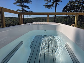 Un jacuzzi con cubierta de madera y vista a una ladera boscosa.