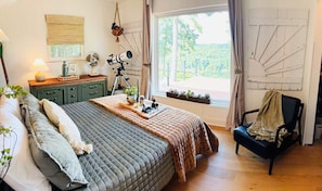 Un dormitorio con cama, escritorio, silla, telescopio y ventana con vistas a zonas verdes.