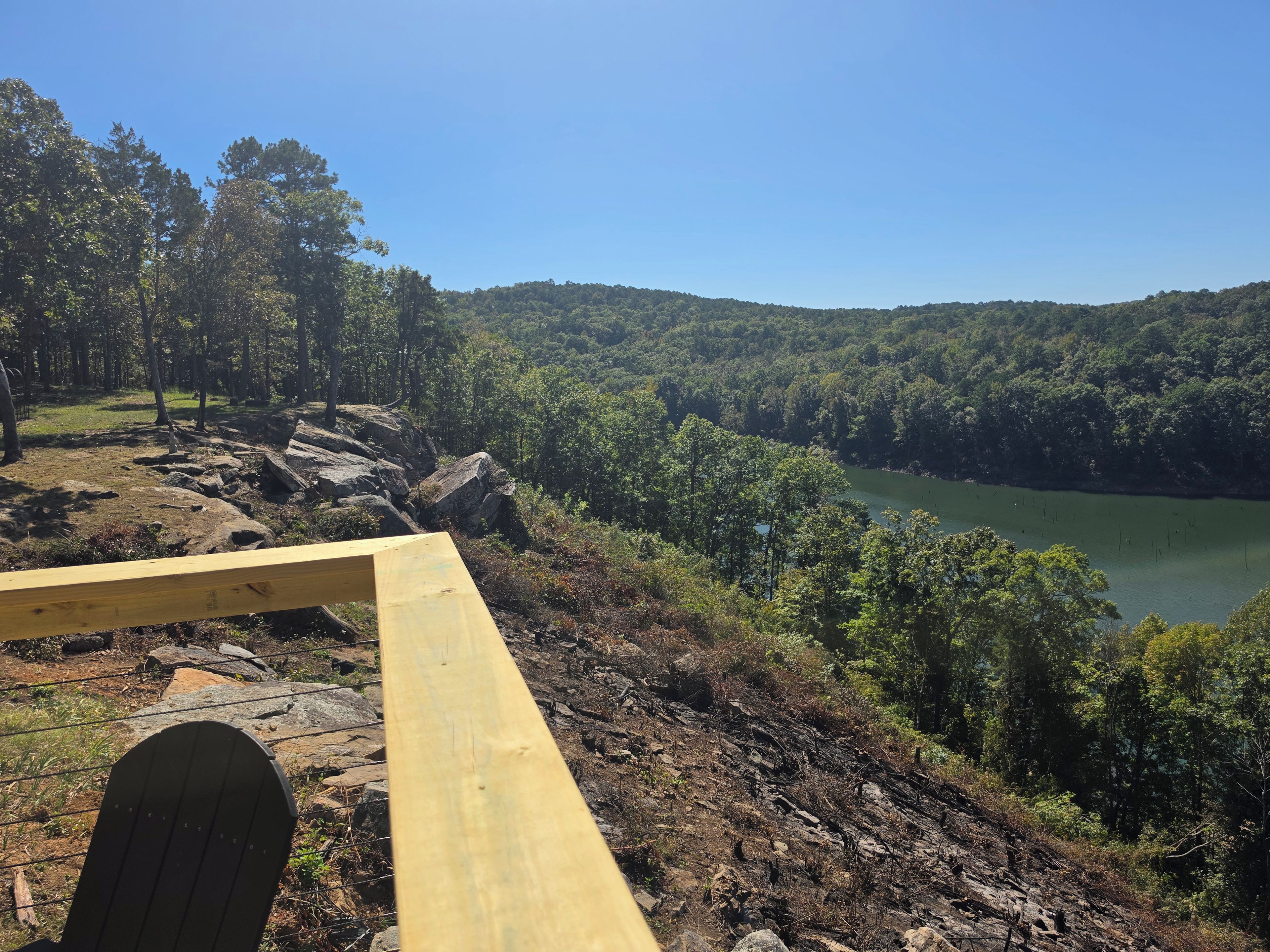 A wooden bench overlooking a lake surrounded by dense forest.