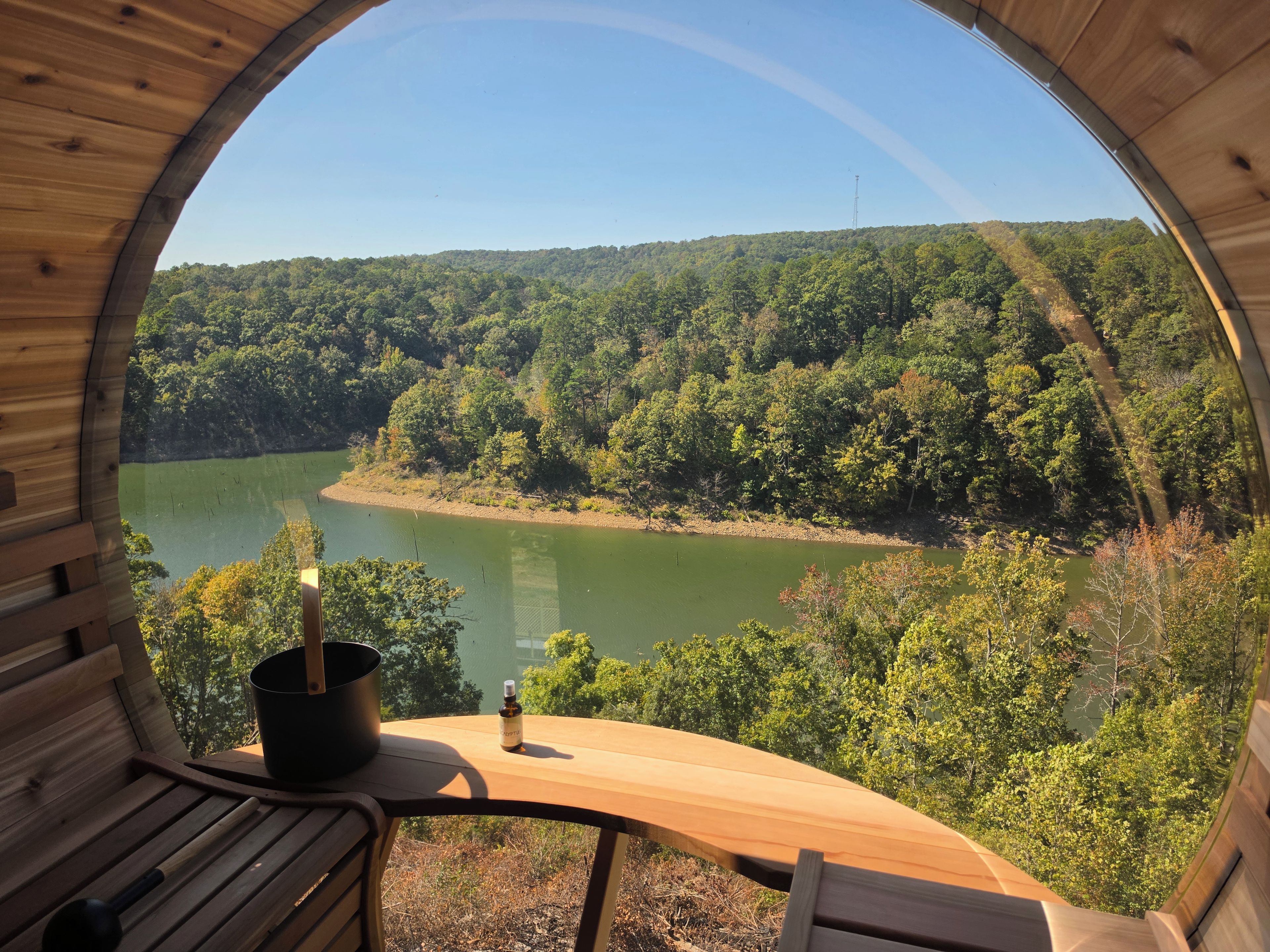 A wooden cabin with a circular window overlooking a lake and forest.