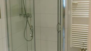 Eine durch eine Glaswand abgetrennte Duschkabine, links ist ein WC sichtbar.