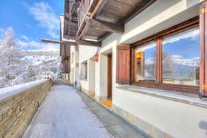 Un balcón cubierto de nieve con vistas a un paisaje montañoso.