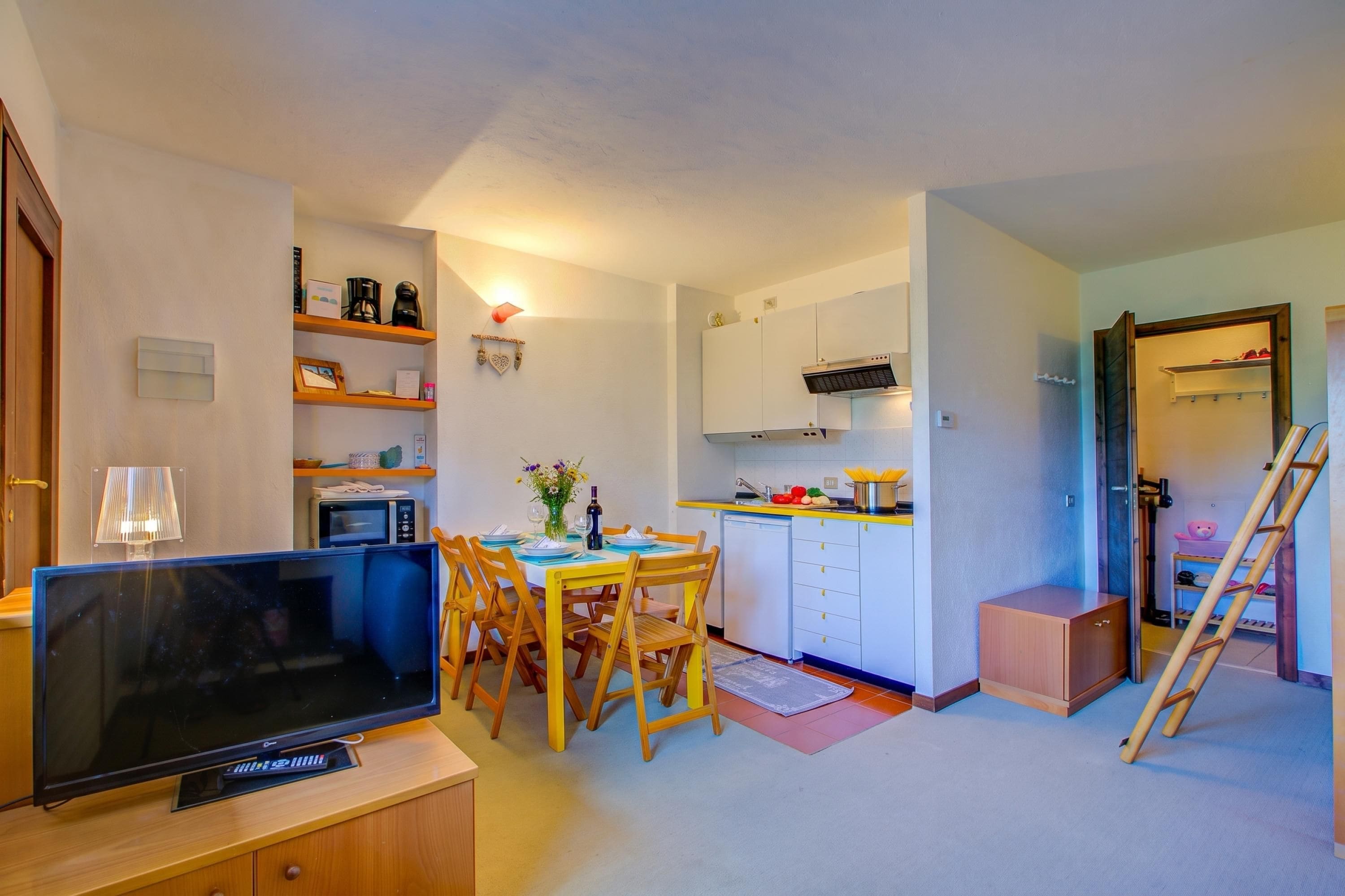 A compact living space with a dining area, kitchenette, and a television.