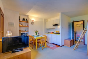 Un espacio habitable compacto con comedor, kitchenette y televisor.