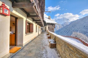 Un sendero nevado que lleva a un edificio con balcones de madera y un farolillo rojo.