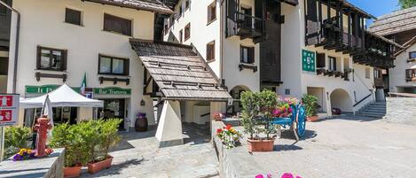 A traditional European building with a bar, outdoor seating, and potted plants.