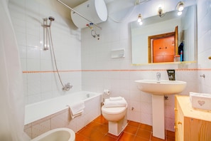 Un baño con bañera, inodoro, lavamanos y ducha.