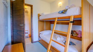 A bunk bed with a ladder, a wooden wardrobe, and a small table with a magazine. - Appartamento I Larici (Sauze di Cesana)
