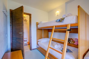 Ein Stockbett mit einer Stehle, ein Holzschrank und ein kleiner Tisch mit einer Zeitschrift.