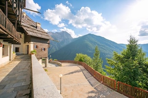 Un edificio de madera tradicional con una escalera de piedra que lleva a una plataforma con vistas a un paisaje montañoso.