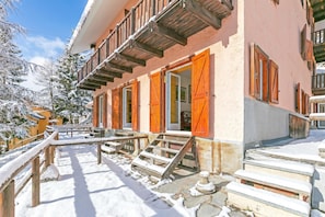 A building with a balcony, wooden steps, and snow-covered surroundings. - Appartamento La Radura (Claviere)