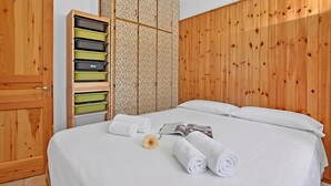 A hotel room with a wooden wardrobe, a bed with white linens, and a large wooden panel wall. - Appartamento La Radura (Claviere)