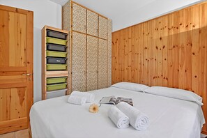 Una habitación de hotel con un armario de madera, una cama con ropa blanca y un gran panel de pared de madera.