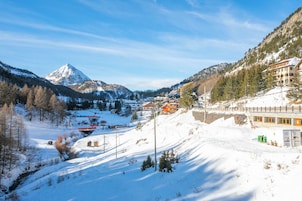 Uma cidade com paisagem de montanha coberta de neve, com um pico imponente, edifícios e um teleférico.