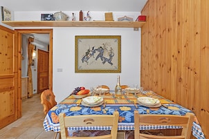 Uma sala de jantar com uma mesa posta para quatro pessoas, rodeada por cadeiras de madeira.