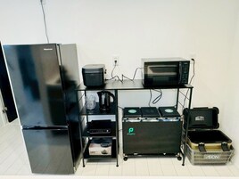 Una kitchenette compacta equipada con un refrigerador Hisense, un microondas, una cafetera y un horno pequeño.