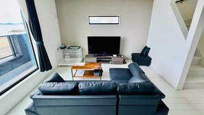 A modern living room with a sectional sofa, a flat-screen TV, a coffee table, and a pet cage.