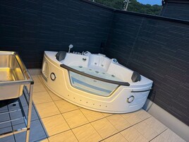 Una bañera de hidromasaje con asiento incorporado y controles, un lavamanos metálico y un piso de baldosas.