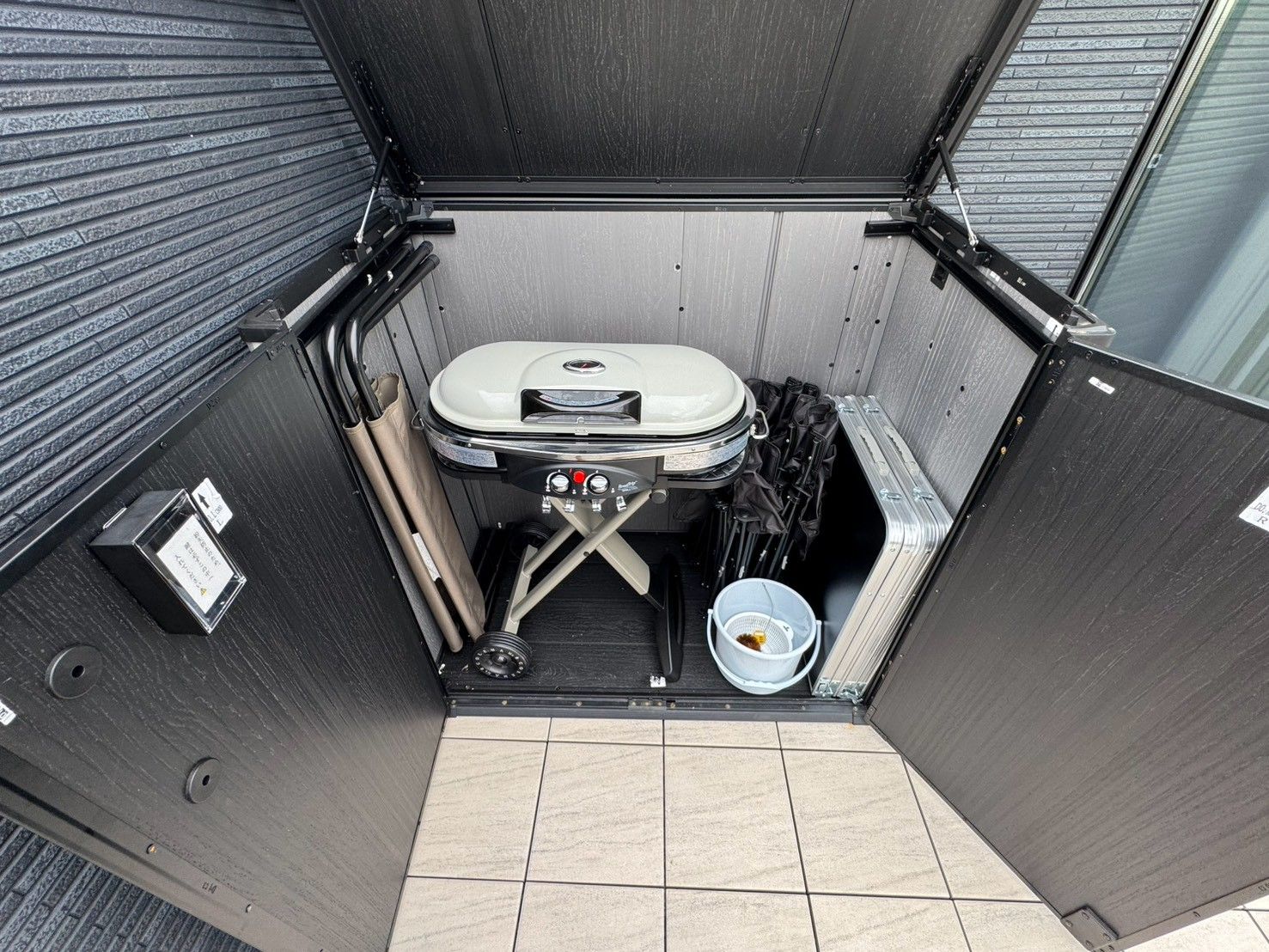 A compact, enclosed space with a portable toilet, a small trash bin, and a metal container on the floor.