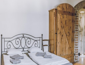 A bed with a metal headboard, white bedding, and two towels. A wooden wardrobe is to the right. - Country Stay for Two Guests (Janowice Wielkie)
