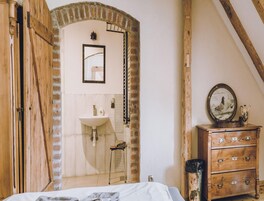 Un dormitorio con un armario de madera, una cómoda, un espejo y una pared de ladrillo.