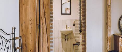 Una habitación con cama, armario de madera y baño con lavabo y ducha.