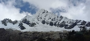 A snow-covered mountain range with rocky outcrops and sparse vegetation at the base.