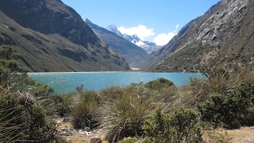 A mountainous landscape with a clear blue lake surrounded by rocky terrain and sparse vegetation.