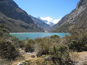 Un paisaje montañoso con un lago azul cristalino rodeado de terreno rocoso y vegetación escasa.