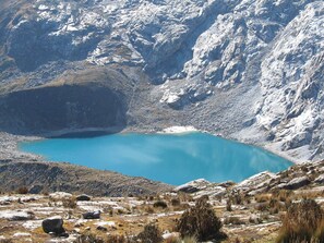 A mountainous landscape with a clear blue lake surrounded by rocky terrain and sparse vegetation.