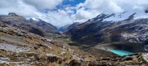 A mountainous landscape with a valley and a turquoise lake.