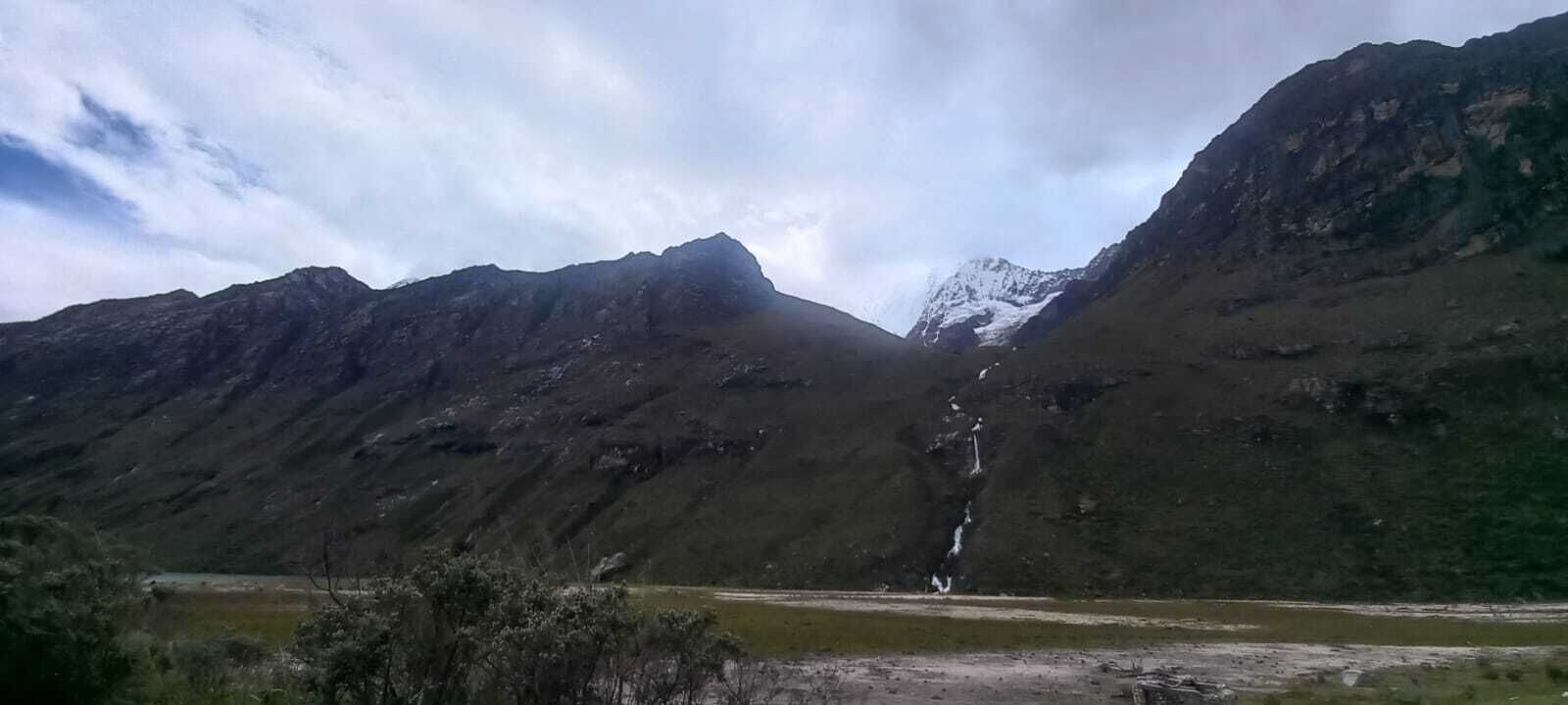 Un paisaje montañoso con una cascada y un lago pequeño.