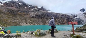 A mountainous landscape with a turquoise lake, rocky terrain, and a sign indicating the elevation of Arhuaycocha.