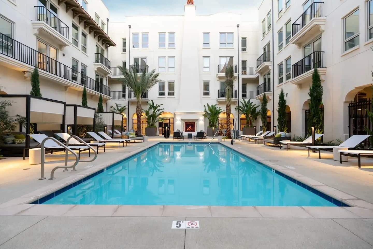 A pool area with lounge chairs and a fire feature in the center.