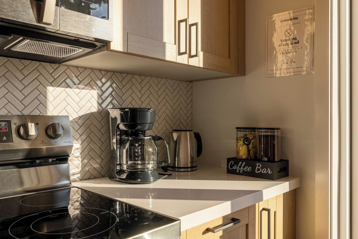 A modern kitchen with a coffee maker, kettle, and a coffee bar sign.