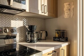 Una cocina moderna con cafetera, hervidor y un letrero que dice 'Coffee Bar'.