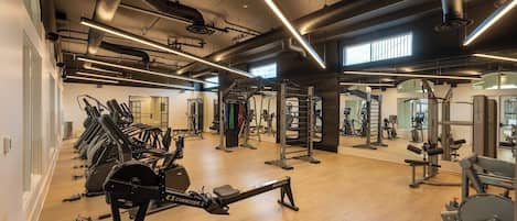A gym with treadmills, weight machines, and a mirrored wall.