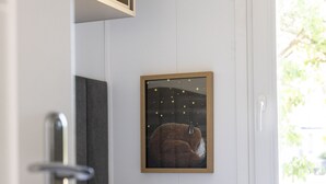 Makuuhuone, jossa on sänky, tyynyjä, seinällä oleva kehystetty kuva ja ikkuna.