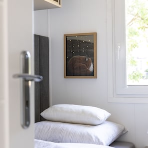 Ein Schlafzimmer mit einem Bett, Kissen, einem gerahmten Bild an der Wand und einem Fenster.