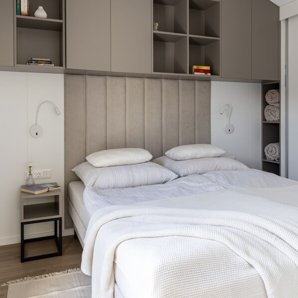 A modern bedroom with a large bed, bedside tables, and built-in shelving.