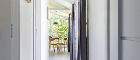 A corridor with a dining area at the end, featuring a table and chairs.