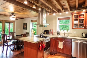 A kitchen with wooden cabinets, a central island, a stove, and a sink. - Red Farmhouse By The Creek (Scott Township)