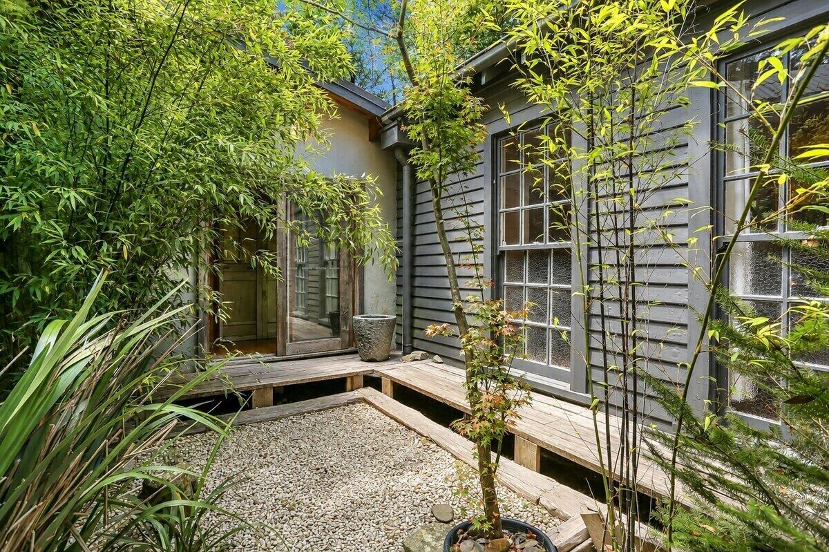 Un jardin de style japonais traditionnel, agrémenté d’une terrasse en bois, d’une lanterne en pierre et de plantes de bambou.